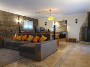 a living room with a gray couch with orange pillows at Casa dos Chãos in Cabeceiras de Basto