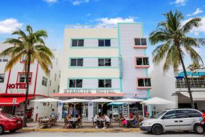 een wit gebouw met palmbomen ervoor bij Starlite Hotel in Miami Beach