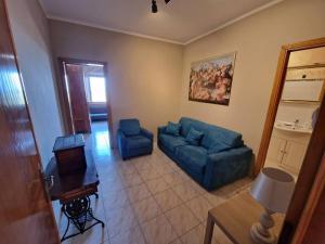 un soggiorno con divano blu e sedie di Casa Elena in Chianni a Chianni