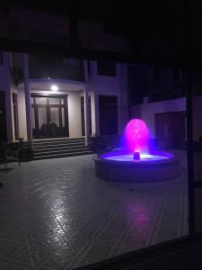 una fuente en un patio por la noche con luces púrpuras en Uzbek House, en Samarkand