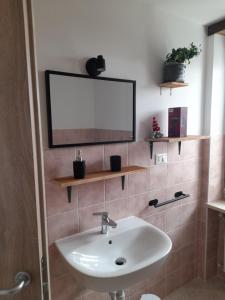 a bathroom with a sink and a tv on the wall at La Mëisun in Perrero
