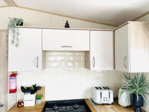 a kitchen with white cabinets and a stove top oven at Sea Breeze in Scarborough