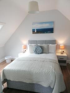 1 dormitorio con 1 cama blanca y 2 lámparas en Atlantic way Apartment 1, en Breaghwy