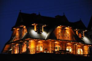 Una casa iluminada por la noche con luces encendidas en Szaflary Dom en Szaflary