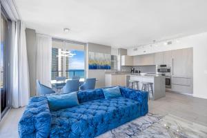 a living room with a blue couch and a kitchen at HYDE BEACH HOUSE RESORT #2101 - MILLION APARTMENT 2BD/2BA. DIRECT OCEAN VIEW. 1 MIN FROM BEACH. 6 GUESTS. in Hollywood