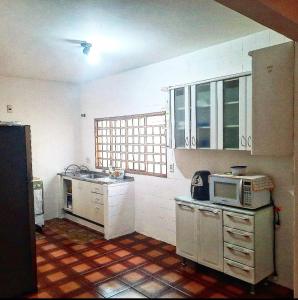 een keuken met witte kasten en een magnetron bij POUSADA ROSA BRANCA in Uberlândia