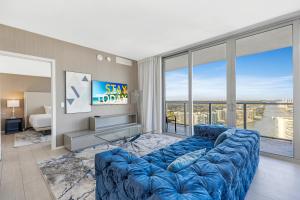 a large blue couch in a living room with a large window at HYDE BEACH HOUSE RESORT #2101 - MILLION APARTMENT 2BD/2BA. DIRECT OCEAN VIEW. 1 MIN FROM BEACH. 6 GUESTS. in Hollywood
