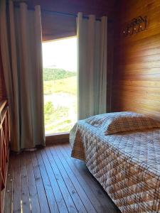 a bedroom with a bed and a large window at Chalé dos Canyons Rio do Rastro in Bom Jardim da Serra +11 photos