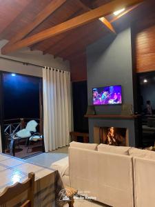 a living room with a couch and a tv over a fireplace at Chalé dos Canyons Rio do Rastro in Bom Jardim da Serra