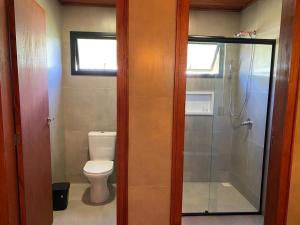 a bathroom with a toilet and a glass shower at Chalé dos Canyons Rio do Rastro in Bom Jardim da Serra +11 photos