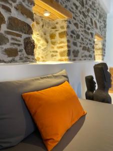 an orange pillow sitting next to a stone wall at MY Volissos Apartments in Volissos