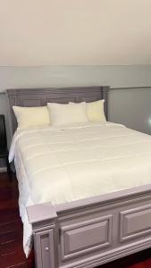ein großes weißes Bett mit weißer Bettwäsche und Kissen in der Unterkunft Odyssey Suites Loft Apartment in Georgetown