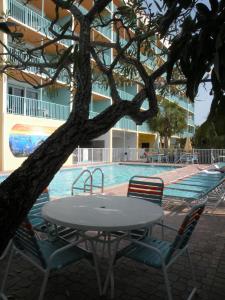 una mesa y sillas frente a una piscina en South Beach Condo Hotel, en St Pete Beach