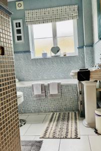 a bathroom with a tub and a sink and a window at Woodbriar in Penmaen-mawr