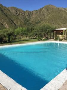 uma grande piscina azul com montanhas ao fundo em La Soñada de La Majadita em San Agustín de Valle Fértil