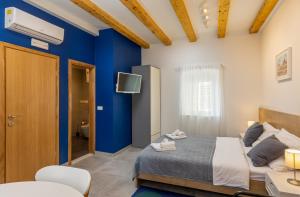 a bedroom with blue walls and a bed and a tv at Blue sea Volantina in Dubrovnik