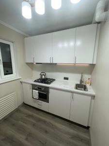 una pequeña cocina con armarios blancos y fregadero en Moderns, gaišs, plašs! A++ 3 istabu dzīvoklis, en Riga