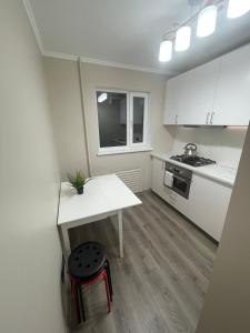 una pequeña cocina con armarios blancos, mesa y taburete en Moderns, gaišs, plašs! A++ 3 istabu dzīvoklis, en Riga