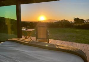 a bed in a room with a view of the sunset at Kokomea PurePod in Te Horo
