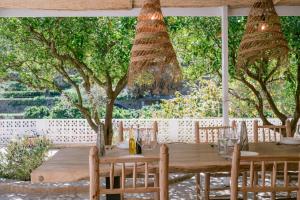 une table et des chaises en bois dans un jardin arboré dans l'établissement Valley Club Ibiza - Boutique Agroturismo, à Sant Joan de Labritja