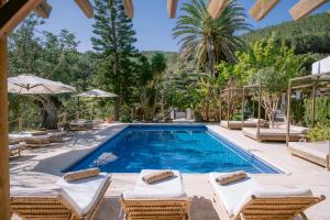 een zwembad met ligstoelen en een villa bij Valley Club Ibiza - Boutique Agroturismo in Sant Joan de Labritja