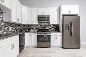 cocina con armarios blancos y nevera de acero inoxidable en Modern 6 Bedrooms Hollywood Urban Home, en Los Ángeles