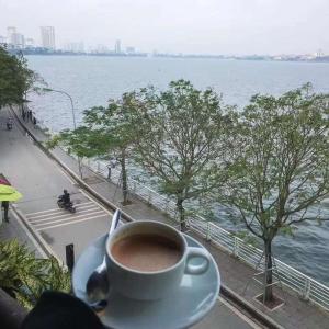 eine Tasse Kaffee auf einem Tisch neben dem Wasser in der Unterkunft H1 Passion in Ho-Chi-Minh-Stadt