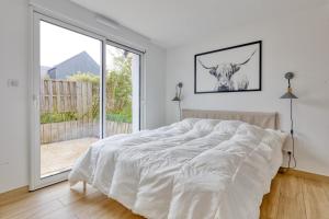 Dormitorio blanco con cama y ventana grande en La Dune de Sable Sainte Marguerite en Pornichet