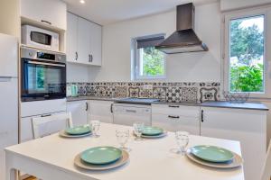 a kitchen with white cabinets and a table with plates and glasses at La Dune de Sable Sainte Marguerite in Pornichet