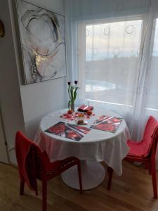 une table avec un chiffon de table blanc et deux chaises rouges dans l'établissement Beau studio avec terrasse et vue EXCLUSIVEMENT POUR NON FUMEURS, à Belmont-sur-Lausanne