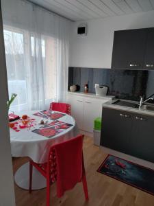una cucina con tavolo, sedie rosse e lavandino di Beau studio avec terrasse et vue EXCLUSIVEMENT POUR NON FUMEURS a Belmont-sur-Lausanne