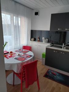 una cocina con mesa con sillas rojas y fregadero en Beau studio meublé POUR NON FUMEURS avec terrasse et vue, en Belmont-sur-Lausanne