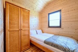 a small bed in a wooden cabin with a window at DOMKI JANTAR PREMIUM in Bobolin