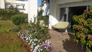 una silla sentada en un patio junto a las flores en Perla à 200 m de la plage en Saidia 