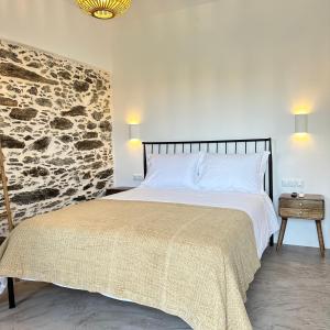 a bedroom with a bed and a stone wall at Peristerionas Estate in Karistos