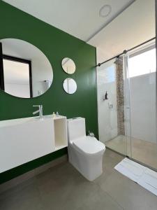 a bathroom with a white toilet and a green wall at Hotel Emerawaa Centro Historico in Ríohacha