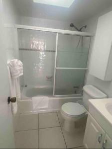 La salle de bains blanche est pourvue d'une douche et de toilettes. dans l'établissement Aloha Condominium On the Intracoastal-Walk to the Beach, à Pompano Beach