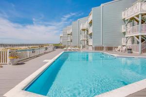a swimming pool in front of a building at Salt and Light Oceanfront Condo with Pool and Elevator in Ocean Isle Beach