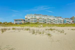 a hotel on the beach with a sandy beach at Salt and Light Oceanfront Condo with Pool and Elevator in Ocean Isle Beach