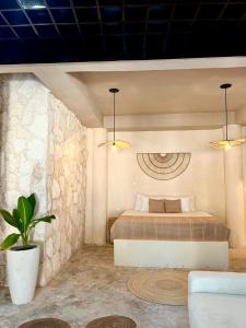 een slaapkamer met een bed en een potplant bij Alquimia Hotel Boutique in Tulum