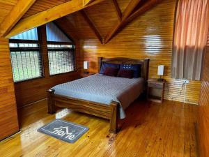 a bedroom with a bed in a wooden room at La Cabaña 2015 in Paso Ancho