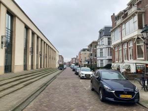 een rij auto's geparkeerd op een straat met gebouwen bij Hotel Poseidon in Scheveningen