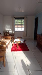 a living room with a table on a red rug at Casa Vista para Serra in Tiradentes