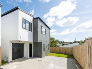 a white house with a garage and a fence at Home Away From Home! in Auckland