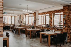 a restaurant with wooden tables and chairs and windows at Hotel Noor Konjic in Konjic