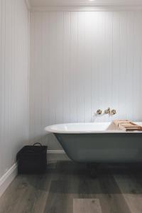 een badkamer met een bad en witte muren bij Ipswich Central Colonial 4&2 house + 2&1 apartment in Ipswich