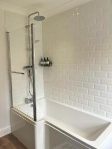 a bathroom with a shower and a white tile wall at Family Friendly House in Norwich with Parking in Norwich