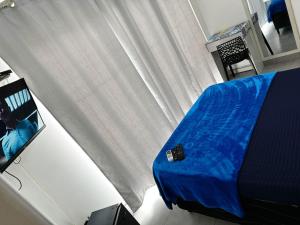 um quarto com uma cama azul e uma televisão em PRAIA DOS ANJOS - SUÍTEs em Arraial do Cabo