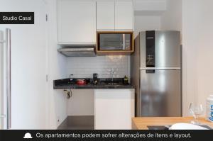 cocina con armarios blancos y nevera de acero inoxidable en Charlie Vila Nova Conceição Jacques Félix en São Paulo