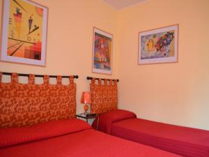 una camera con due letti con lenzuola rosse di A Casa di Carla a Terni